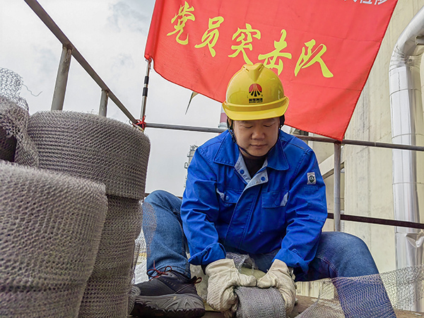 5月10日中午，在動(dòng)力車間三期工藝除氧器平臺上，黨員突擊隊(duì)隊(duì)長李鑫正在纏繞新填料.jpg