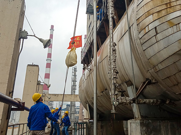 5月10日中午，在動(dòng)力車間三期工藝除氧器地面，黨員突擊隊(duì)隊(duì)員用滑輪往工藝除氧器平臺運(yùn)送鋼絲網(wǎng)，用以纏繞新填料.jpg