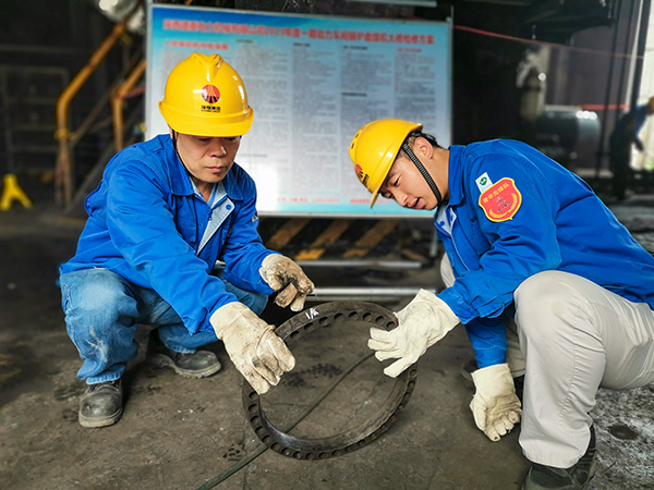 圖三：12日下午14時(shí)，在一期磨煤機(jī)廠房，陜西省技術(shù)能手姬霄給青工張跟潮講解磨煤機(jī)搖臂曲拐內(nèi)環(huán)及動(dòng)作原理。.jpg